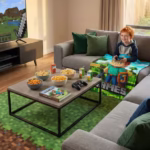 A child playing games in a cozy living room while snuggled under a personalized "James" gamer blanket, with a gaming book and snacks on the coffee table.