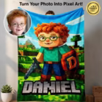 A large custom personalized kids' blanket held up to display an 8-bit pixel art gamer character named Daniel with orange hair and glasses, next to an inset photo of the real boy it was modeled after.
